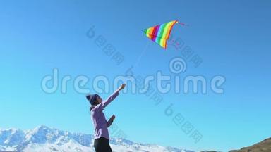 一位年轻女子在高山和冰川的田野里放风筝